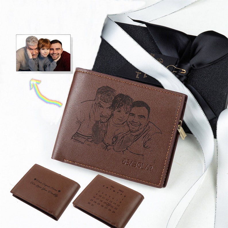 May include: Brown leather wallet with a family portrait engraved on the front. The wallet has a zipper closure and a gold-colored zipper pull. Two smaller wallets are also visible, one with text and the other with a calendar.