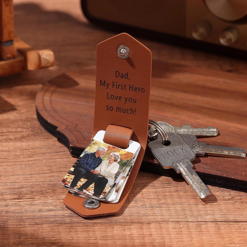 May include: A brown leather keychain with a photo insert and the text "Dad, My First Hero Love you so much!". The keychain holds several keys, including one with "LOCK" printed on it. The photo insert shows an older couple.