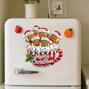 May include: A festive Christmas magnet set featuring gingerbread people with Santa hats in a red mug with the words "Merry Christmas". Includes apple and orange magnets. Names on the gingerbread people include Wyatt, Emma, Lucas, Daniel, Noah, and Oliver.