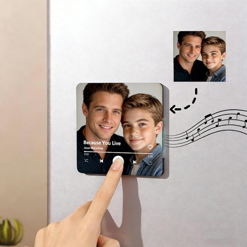 May include: A square magnet featuring a photo of two people, with a music player interface overlay. The song title "Because You Live" by Jesse McCartney is visible. A smaller photo of the same people is also present. A finger touches the play button.