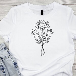 May include: White t-shirt with a black line drawing of a bouquet of flowers, including a sunflower, a rose, and a daisy.