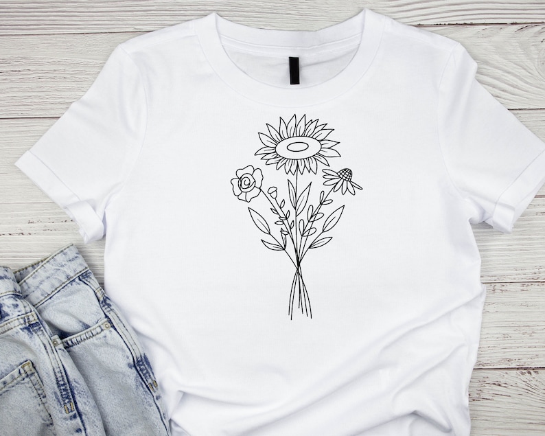 May include: White t-shirt with a black line drawing of a bouquet of flowers, including a sunflower, a rose, and a daisy.