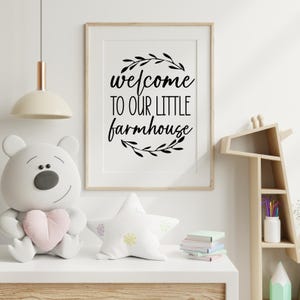 May include: Black and white printable wall art with the text "welcome to our little farmhouse" surrounded by a wreath of leaves.