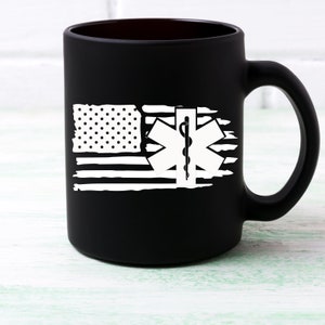 May include: Black matte ceramic coffee mug with a white distressed American flag design and a white medical symbol with a snake and staff.