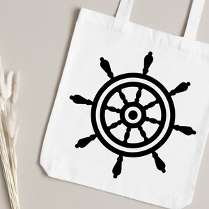 May include: A white tote bag with a black ship's wheel design. The wheel has eight spokes and a central hub.