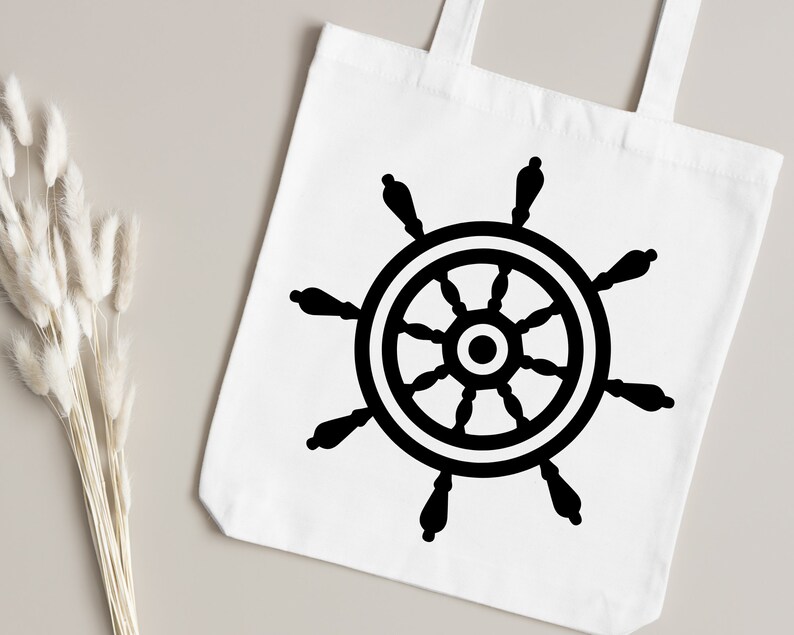 May include: A white tote bag with a black ship's wheel design. The wheel has eight spokes and a central hub.