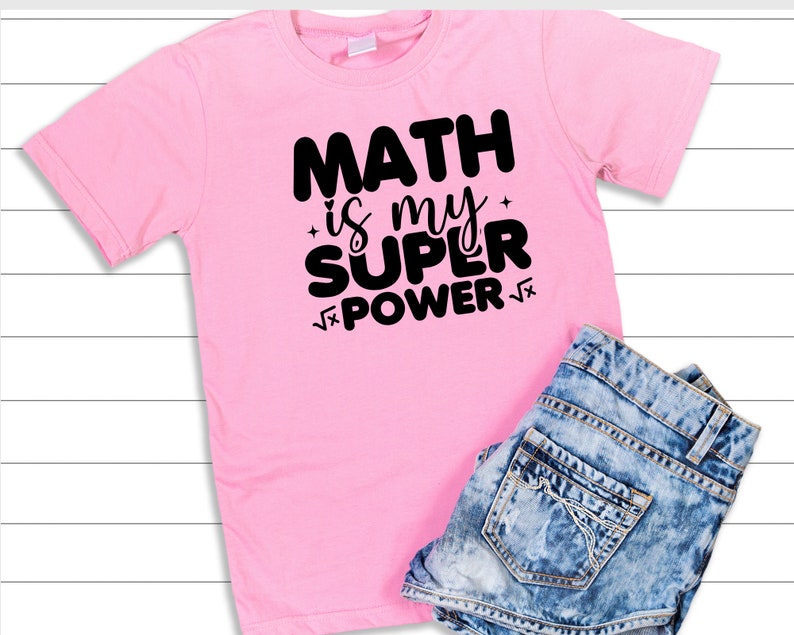 Puede incluir: Camiseta rosa con texto negro que dice "Math is my super power" con un s&iacute;mbolo de ra&iacute;z cuadrada antes y despu&eacute;s de la palabra "power".