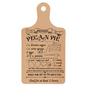 Pode incluir: Uma t&aacute;bua de cortar de madeira castanho com uma receita para torta de pecan caseira. A receita inclui ingredientes como a&ccedil;&uacute;car mascavo, xarope de milho, ovos, nozes pecan, manteiga, baunilha e sal. A t&aacute;bua tamb&eacute;m inclui instru&ccedil;&otilde;es para assar a torta por 60 a 70 minutos e deixar esfriar por pelo menos 2 horas.