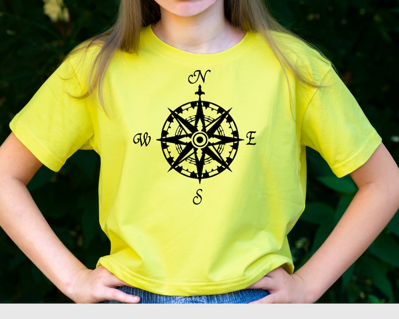 May include: A yellow t-shirt with a black compass design. The compass has the letters N, S, E, and W around it.