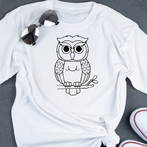 May include: White t-shirt with a black line drawing of an owl perched on a branch.