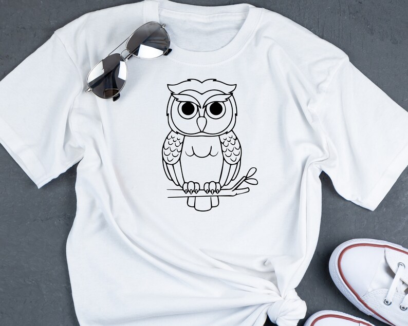 May include: White t-shirt with a black line drawing of an owl perched on a branch.