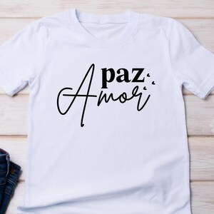 May include: White t-shirt with black text that reads "A paz... Amor".