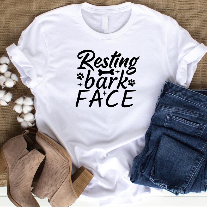 Puede incluir: Camiseta blanca con texto negro que dice "Resting bark face" con huellas de patas y un gr&aacute;fico de hueso.
