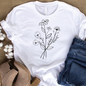 May include: White t-shirt with a black line drawing of a bouquet of flowers. The flowers include daisies and other small flowers.
