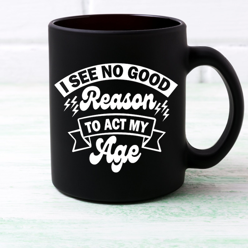 May include: Black coffee mug with white text that reads "I see no good reason to act my age".