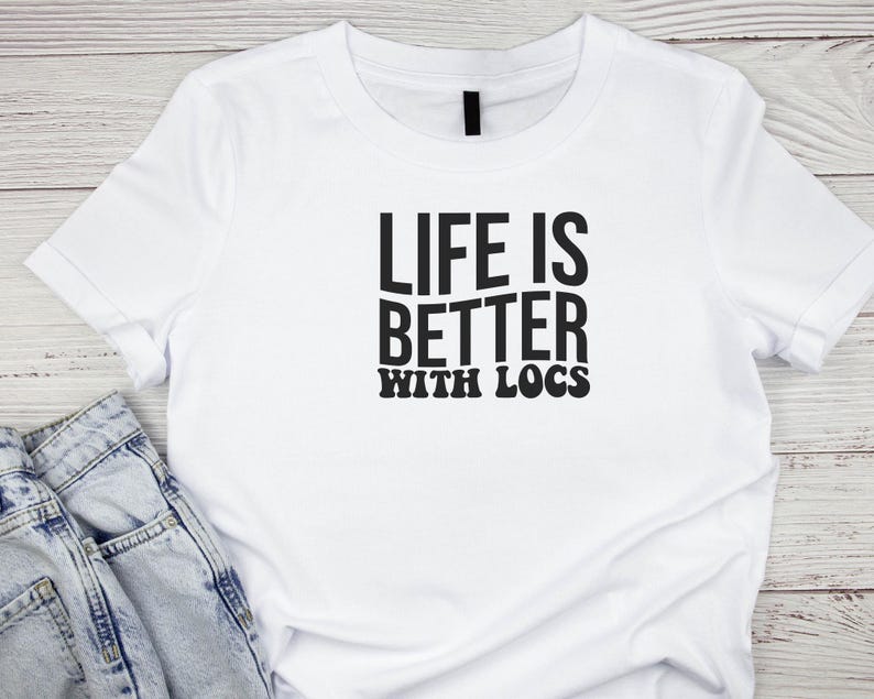 May include: White t-shirt with black text that reads "Life is better with locs".