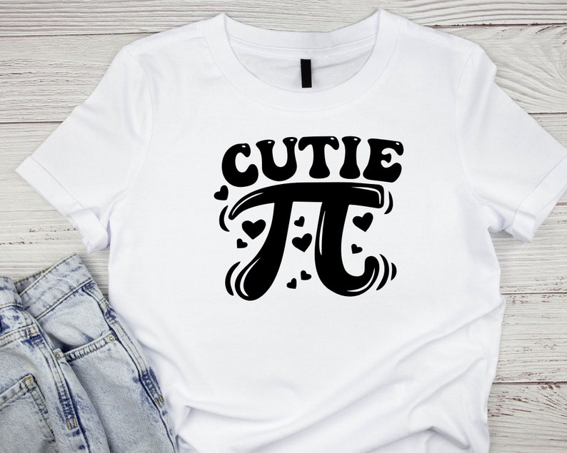 Puede incluir: Camiseta blanca con texto negro que dice "cutie pi" con un s&iacute;mbolo pi estilizado y corazones alrededor.