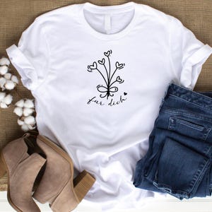 May include: White t-shirt with a black graphic of a bouquet of hearts with a bow and the text "f&uuml;r dich".