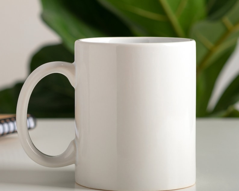 May include: A white ceramic mug with a rounded handle. The mug is empty and ready to be filled with a hot beverage.