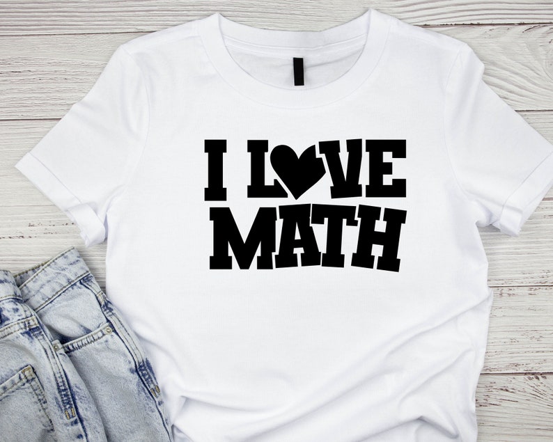 Puede incluir: Camiseta blanca con texto negro que dice "ME ENCANTA LAS MATEM&Aacute;TICAS" con un coraz&oacute;n que reemplaza la "O".