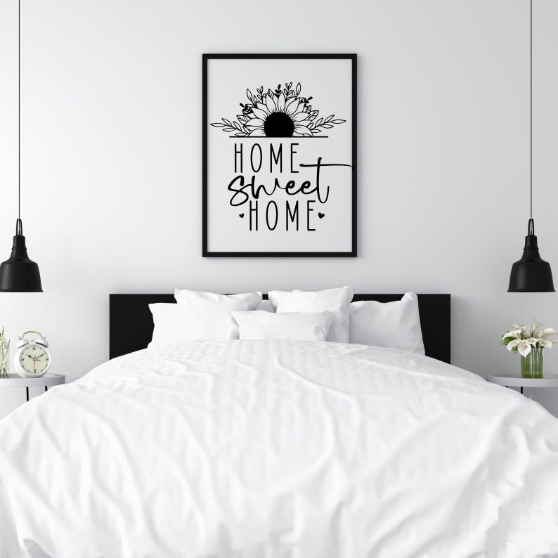 May include: Black and white print with a sunflower design and the text "Home Sweet Home" in a white bedroom with a white bed and black bedside tables.