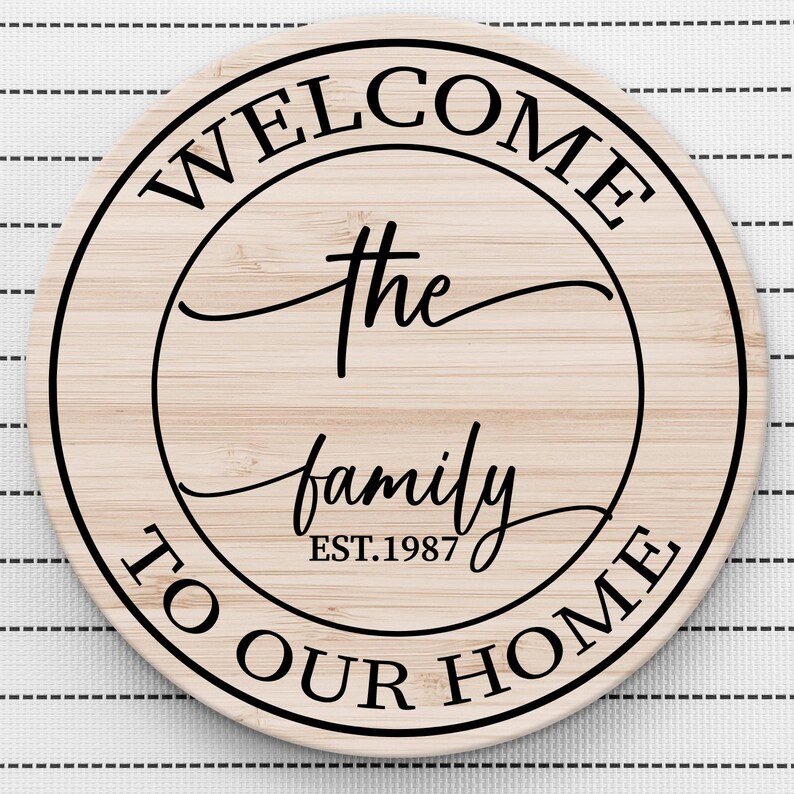 May include: A round wooden sign with the text "Welcome the family est. 1987 to our home" in a black circle.