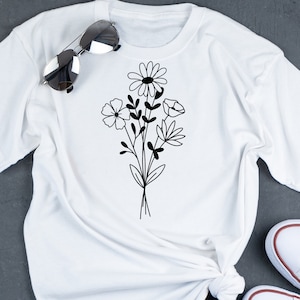 May include: White t-shirt with a black floral design featuring a daisy, a poppy, and other flowers.
