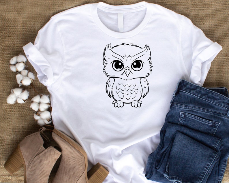 May include: White t-shirt with a black and white cartoon owl graphic.