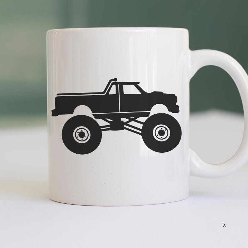 May include: White ceramic coffee mug with a black silhouette of a monster truck. The truck has large tires and a raised suspension.