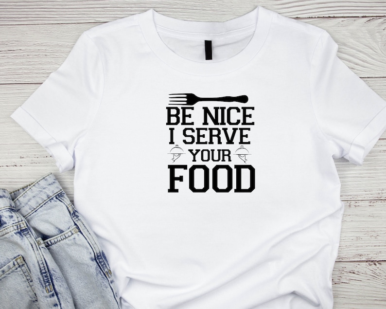 May include: White t-shirt with black text that reads "Be Nice I Serve Your Food" with a fork and plate graphic.