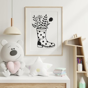 May include: Framed monochrome art print. The image shows a wellington boot with black polka dots, filled with botanical illustrations. The print is in a light wood frame, suitable for a nursery or children's room.