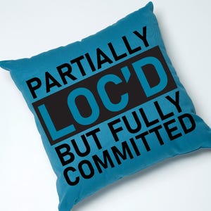 May include: A blue throw pillow with the text "Partially Loc'd But Fully Committed" in black.