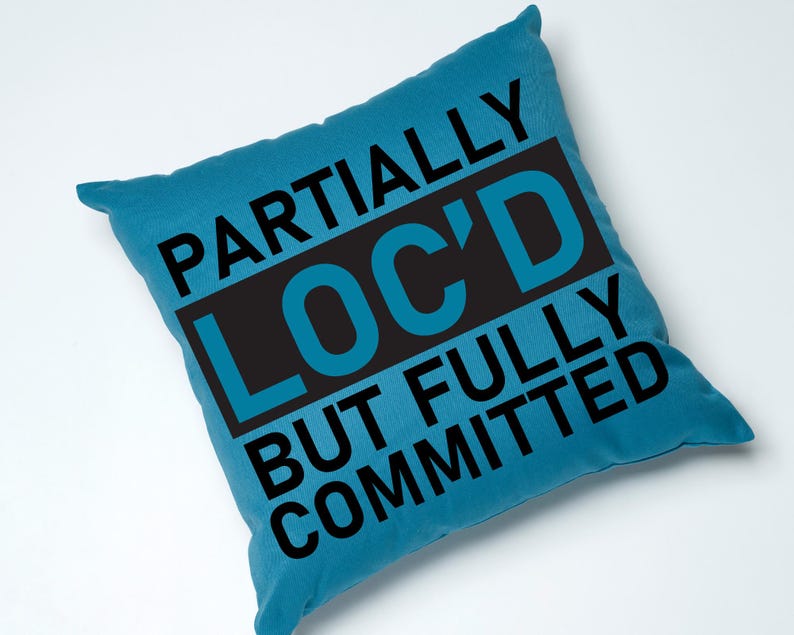 May include: A blue throw pillow with the text "Partially Loc'd But Fully Committed" in black.