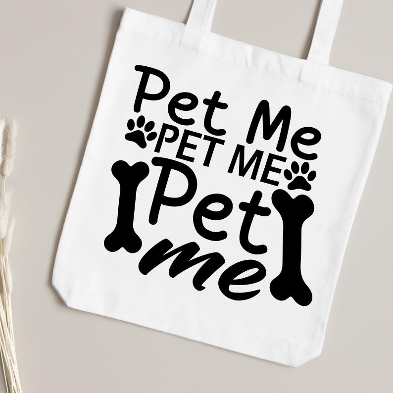 Puede incluir: Bolsa de tela blanca con texto negro que dice "Pet Me Pet Me Pet Me" con huellas de patas y gr&aacute;ficos de huesos.