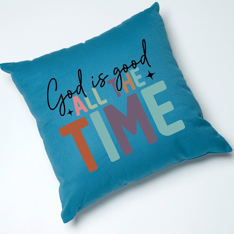 May include: A teal blue throw pillow with the text "God is good all the time" in colorful letters. The letters are in a variety of colors, including orange, pink, green, and purple.