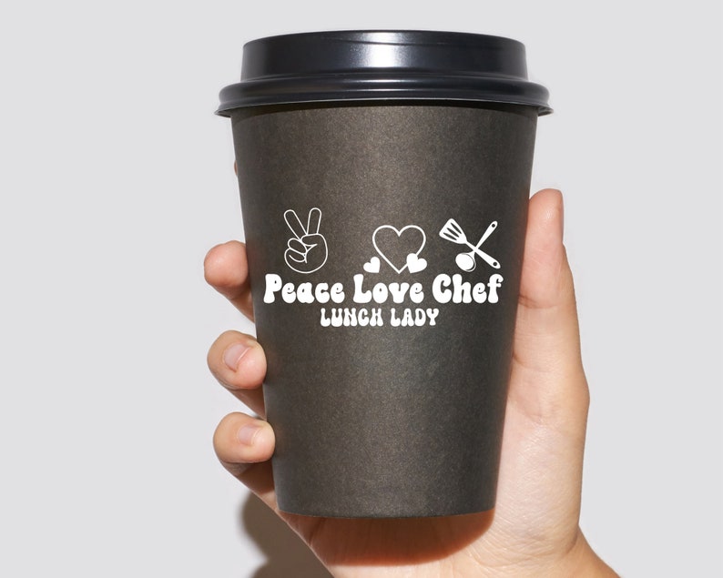May include: A black to-go coffee cup with a white design that says "Peace Love Chef Lunch Lady" with a peace sign, heart, and kitchen utensils.