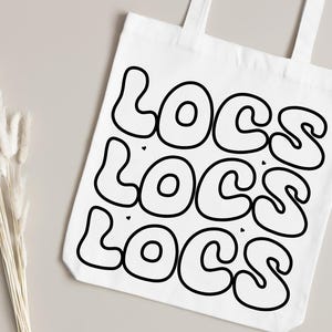 May include: White tote bag with the word "LOCS" repeated three times in a black, stylized font.
