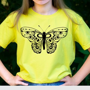 May include: A yellow t-shirt with a black butterfly graphic. The butterfly has intricate details and a geometric design.