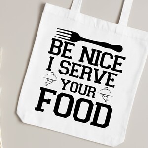 May include: White tote bag with black text that reads "Be Nice I Serve Your Food". The text is in a bold, blocky font. A black fork and a black serving dish are also pictured on the bag.