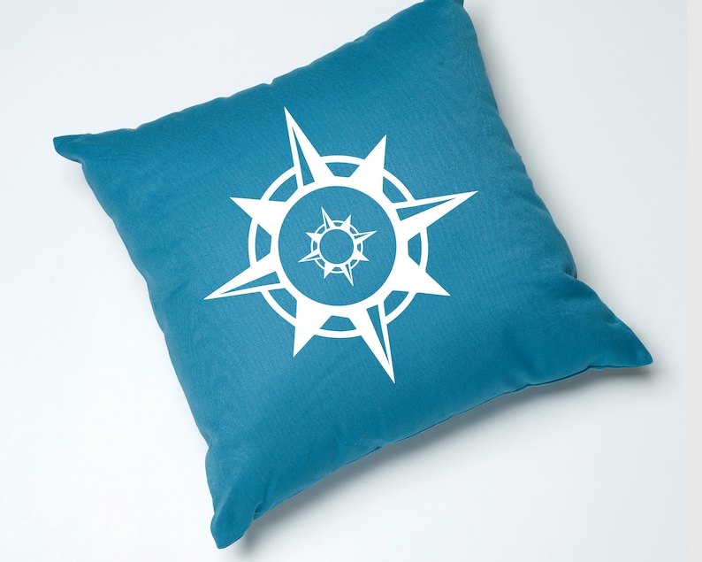 May include: A teal blue throw pillow with a white compass design. The compass has a circle with eight points.