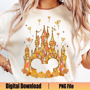 May include: Cream-colored t-shirt featuring a colorful castle design with pumpkins and balloons. The castle is in shades of orange, yellow, and pink. The text "Digital Download | PNG File" is at the bottom.
