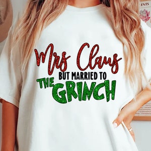 May include: White t-shirt with the text "Mrs. Claus BUT MARRIED TO THE GRINCH". The text is in red and green glitter. The shirt is a festive holiday design.