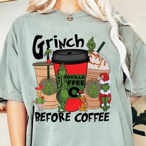 Puede incluir: Camiseta verde claro con un diseño festivo. El diseño presenta al Grinch con tazas de café y el texto "Grinch Before Coffee". La imagen incluye a Cindy Lou Who y Max el perro, todo en un tema navideño.