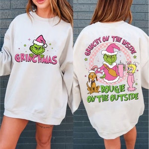 Puede incluir: Una sudadera blanca con un personaje verde del Grinch que lleva un gorro de Papá Noel y el texto "Grinchmas" en la parte delantera. La parte posterior de la sudadera tiene un personaje verde del Grinch que lleva un traje de Papá Noel rosa y el texto "Grinchy on the inside, bougie on the outside".