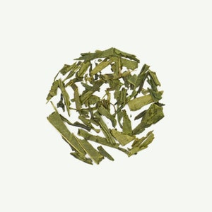 May include: Loose green tea leaves scattered on a white background.