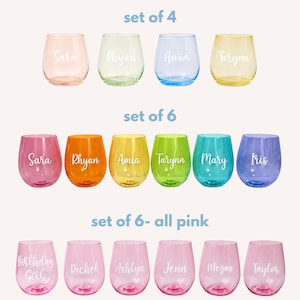 May include: A collection of stemless wine glasses in various colors, including pink, green, blue, yellow, orange, and purple. Each glass features a custom white script name or text, such as Sara, Rhyan, Amia, Tarynn, Mary, Iris, Birthday Girl, Rachel, Ashlyn, Jenn, Megan, and Taylor.