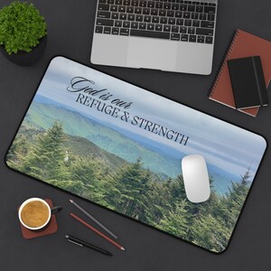May include: A mouse pad with a scenic mountain landscape featuring a blue sky, green trees, and the text "God is our REFUGE & STRENGTH".