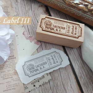 May include: A wooden stamp with the text "LACTATED PEPSIN, N. F. 00187 Alcohol 16 to 19%" engraved on it. The stamp is rectangular and has rounded corners. The text is in a serif font and is centered on the stamp.
