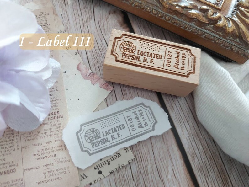 May include: A wooden stamp with the text "LACTATED PEPSIN, N. F. 00187 Alcohol 16 to 19%" engraved on it. The stamp is rectangular and has rounded corners. The text is in a serif font and is centered on the stamp.