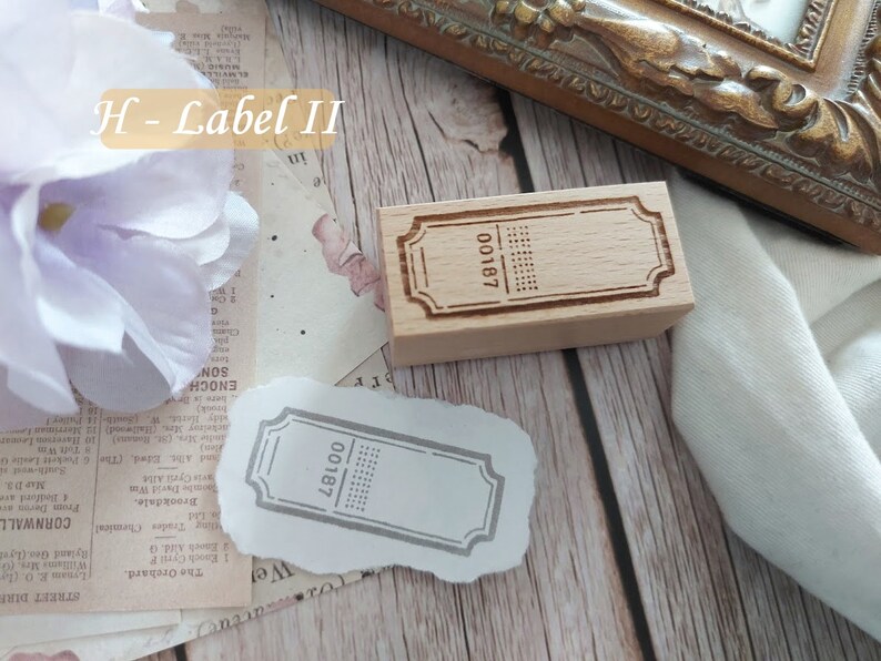 May include: Two wooden stamps with a rectangular shape and a decorative border. The stamps have the text "00187" printed on them. The stamps are on a white surface.